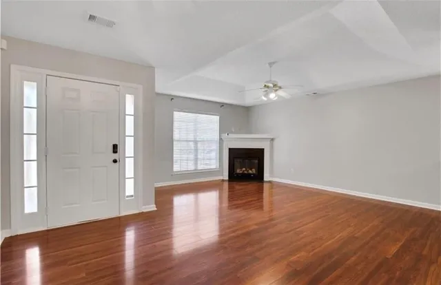 a view of an empty room with wooden floor and a window