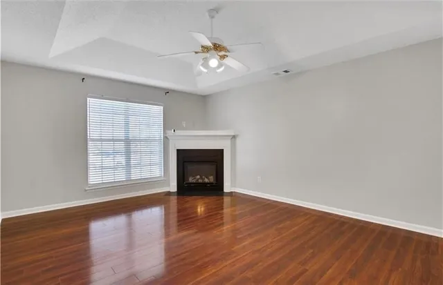 an empty room with wooden floor chandelier and glass door