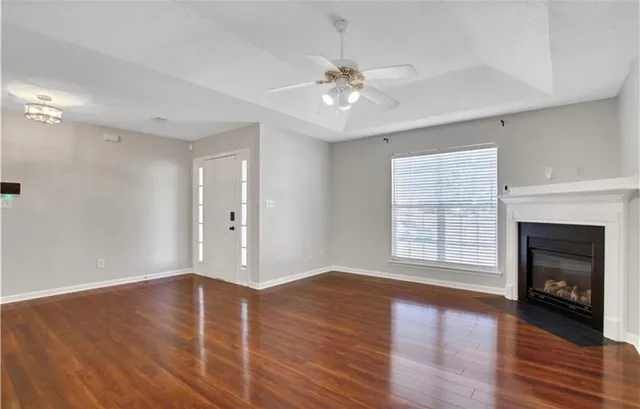 a view of an empty room with wooden floor fireplace and a window