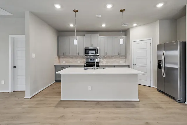 a kitchen with kitchen island stainless steel appliances a sink a stove a microwave and cabinets