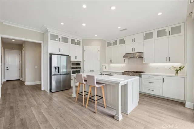 a kitchen with a stove a refrigerator and white cabinets