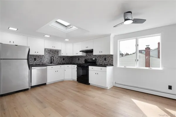 a kitchen with stainless steel appliances granite countertop a refrigerator a sink a stove a microwave and white cabinets