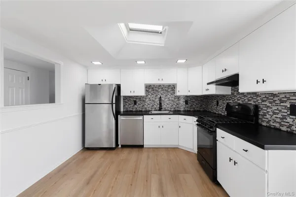 a kitchen with granite countertop a refrigerator stove top oven and sink