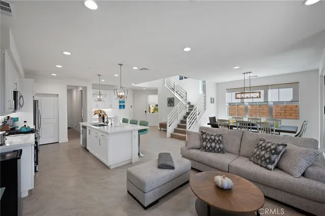 a large kitchen with a counter space a sink appliances and a living room view