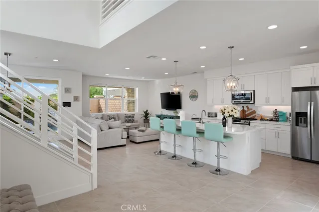 a kitchen with stainless steel appliances granite countertop a refrigerator a stove a sink dishwasher a dining table and chairs with wooden floor