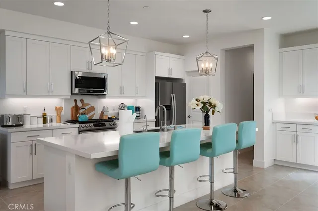 a table with a stove and a vase of white wine sitting on a counter