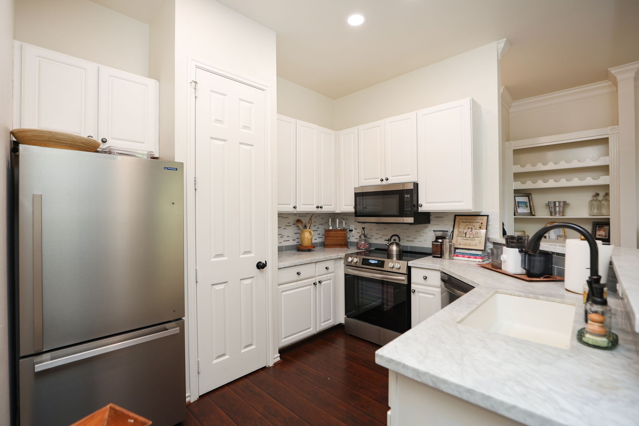 2400 South McCue Road, Unit 104 Houston, TX 77056 - Photo 12 of 38 Entry into kitchen showing the updated appliances and Carra Marble Counter Tops along with new wood flooring.