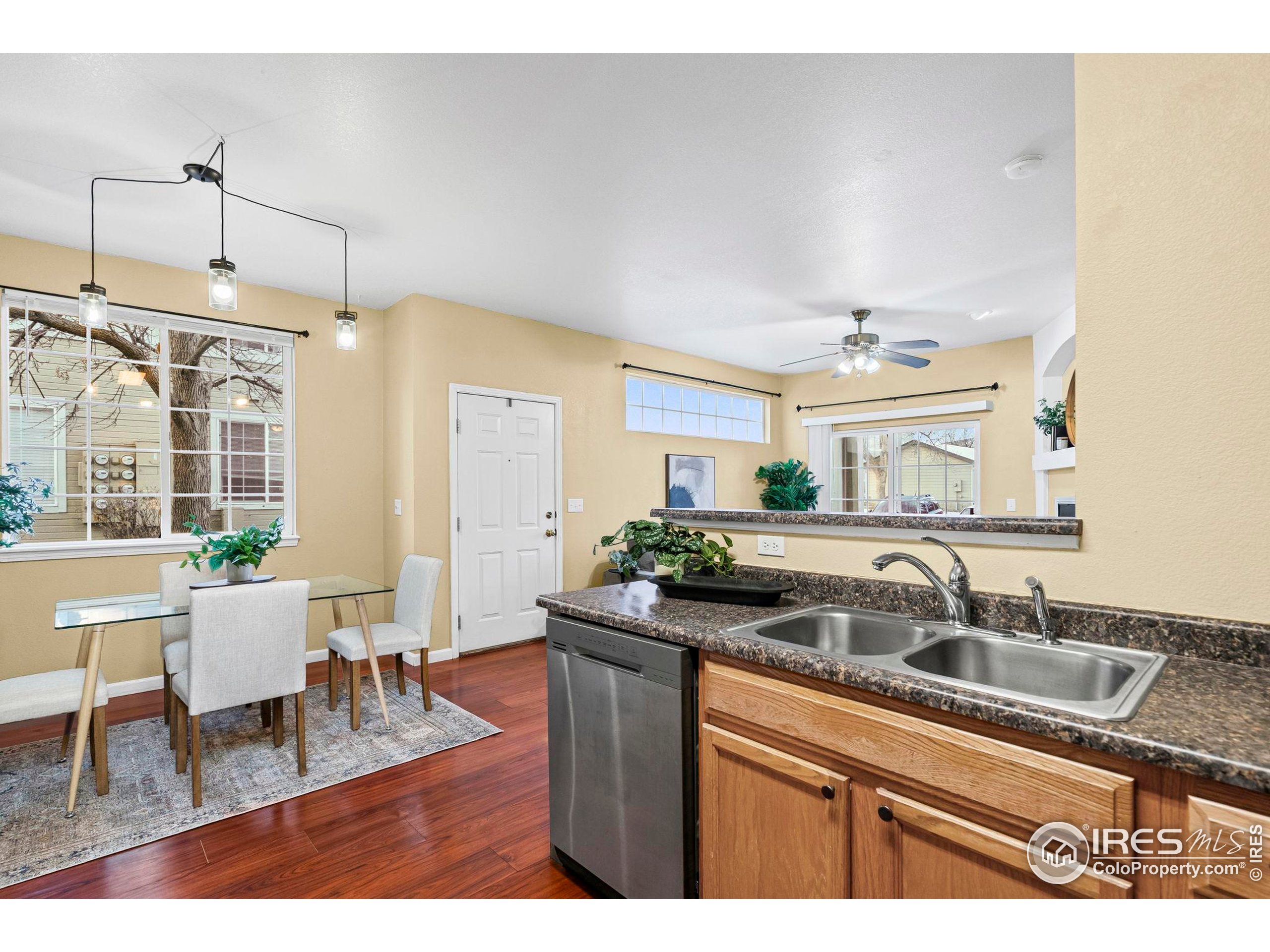 3002 West Elizabeth Street, Unit D Fort Collins, CO 80521 - Photo 15 of 23 a kitchen with a sink dishwasher a dining table and chairs with wooden floor
