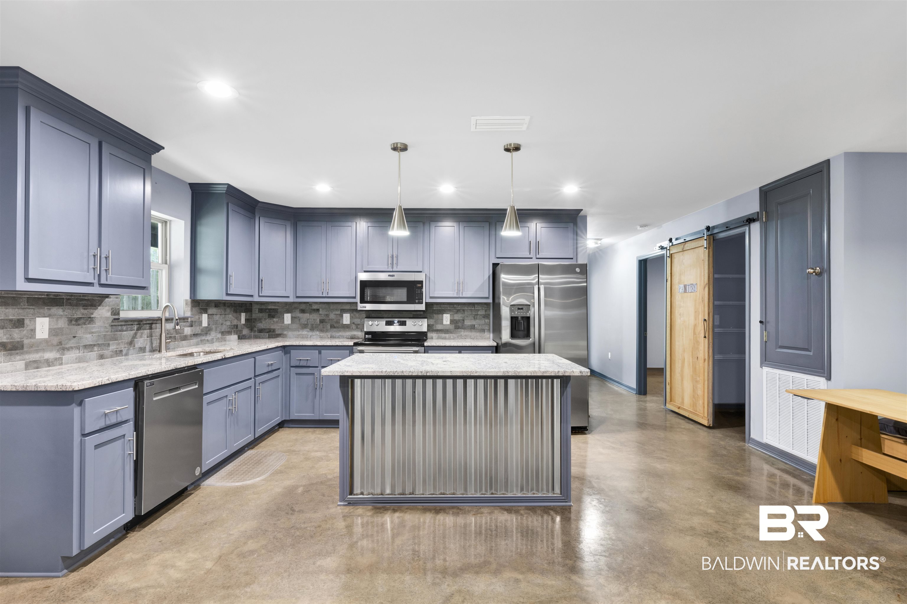 36397 Alexandria Trail Stapleton, AL 36578 - Photo 28 of 65 Kitchen featuring a barn door, finished concrete floors, light stone counters, a kitchen island, and stainless steel appliances