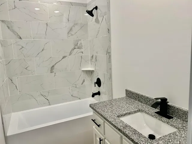 a bathroom with a granite countertop sink a toilet and bathtub