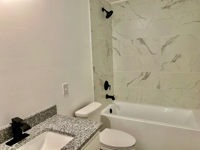 a bathroom with a granite countertop sink toilet and shower