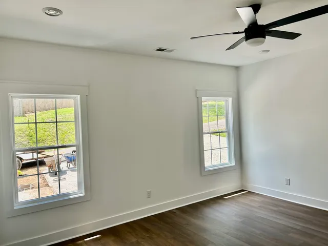a view of an empty room with a window and wooden floor