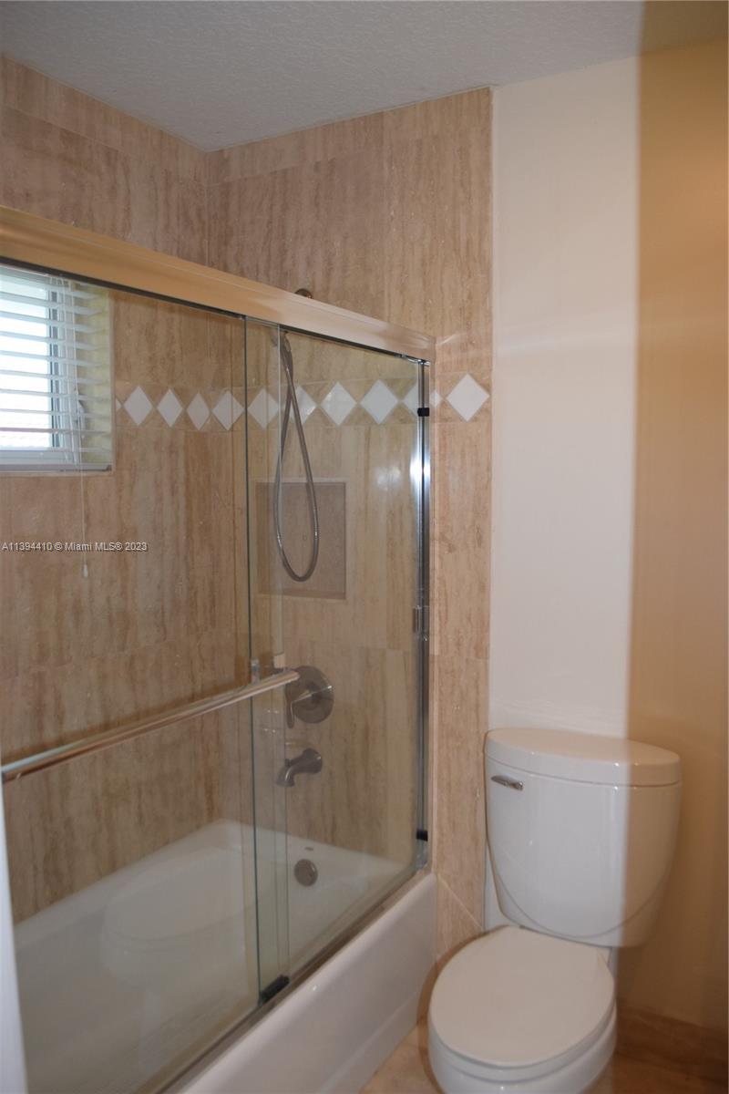 7115 Southwest 69th Court Miami, FL 33143 - Photo 35 of 58 a white toilet sitting next to a bath tub and a shower