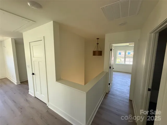 a view of a hallway with wooden floor and windows