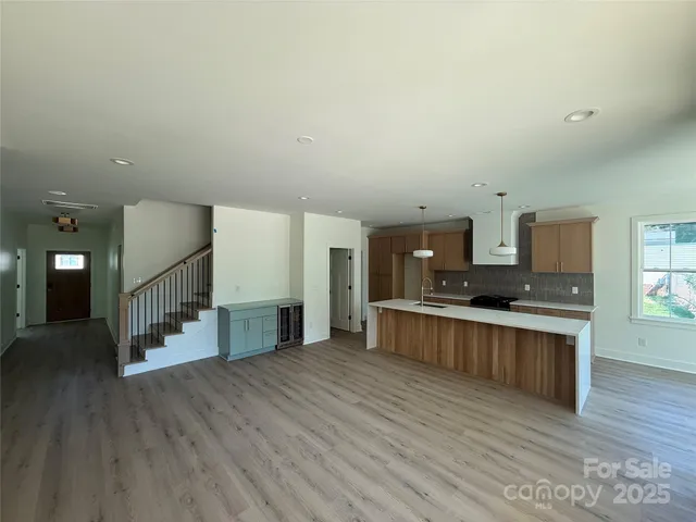 a large kitchen with a center island and wooden floor