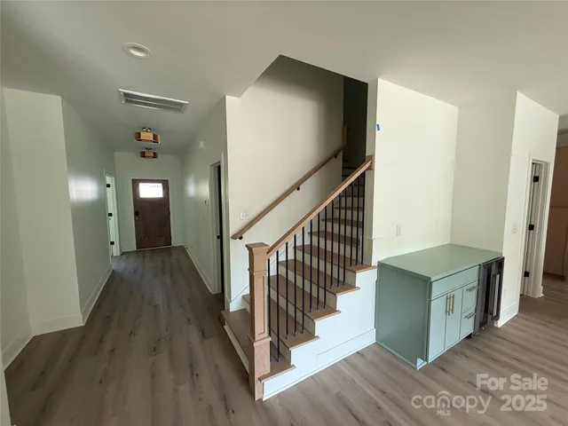 a view of a hallway with wooden floor and stairs