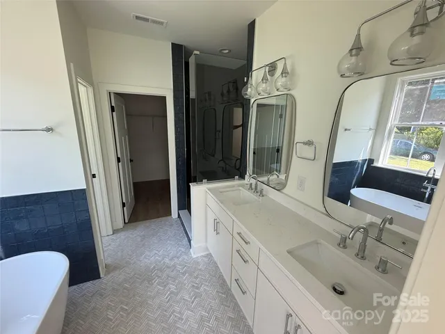 a spacious bathroom with a double vanity sink a mirror and a shower