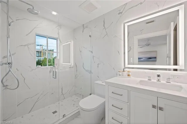 a bathroom with a shower sink vanity mirror and toilet