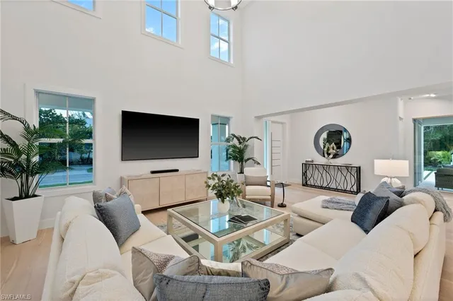 a living room with furniture a flat screen tv and a floor to ceiling window