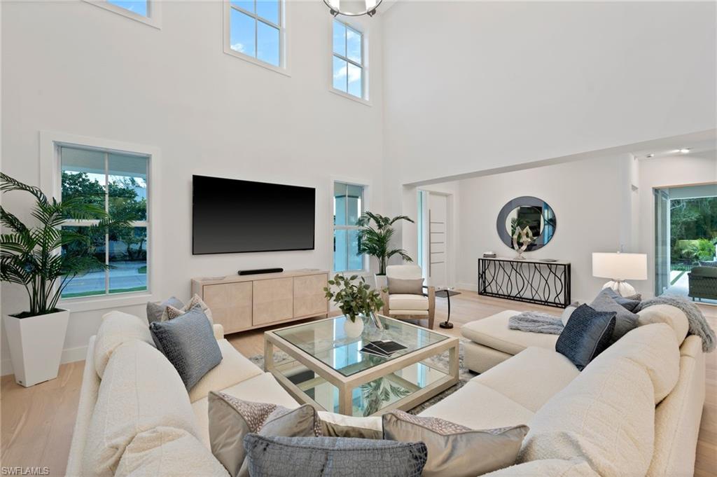 1984 Frederick Street Naples, FL 34112 - Photo 8 of 38 a living room with furniture a flat screen tv and a floor to ceiling window