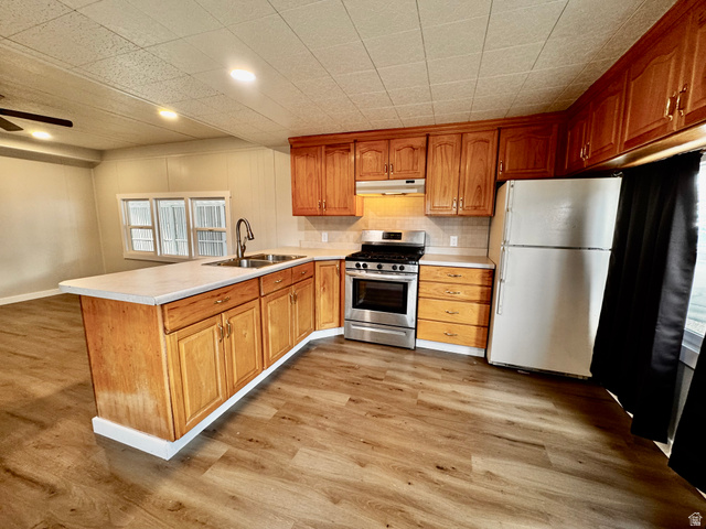 158 Cushing Way Layton, UT 84041 - Photo 5 of 14 Kitchen featuring wood-finish flooring, wood cabinetry, light-colored countertops, a stainless steel range, and a dual basin sink with a gooseneck faucet