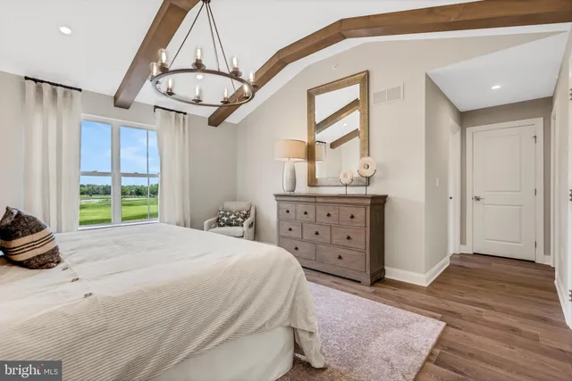 a bedroom with a bed a dresser and wooden floor