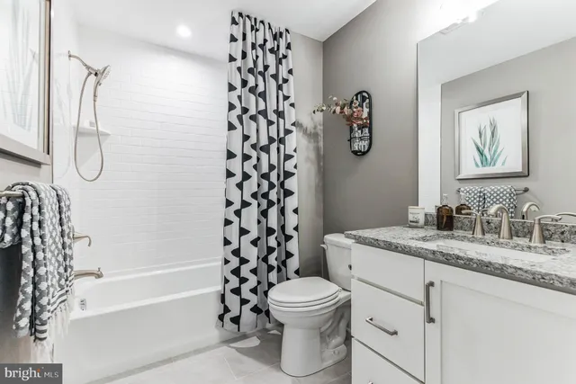 a bathroom with a granite countertop toilet a sink and a shower