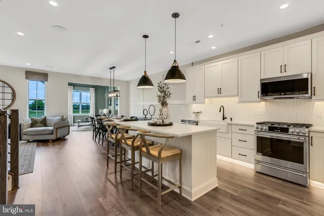 a kitchen with stainless steel appliances a stove a sink a oven a dining table and chairs