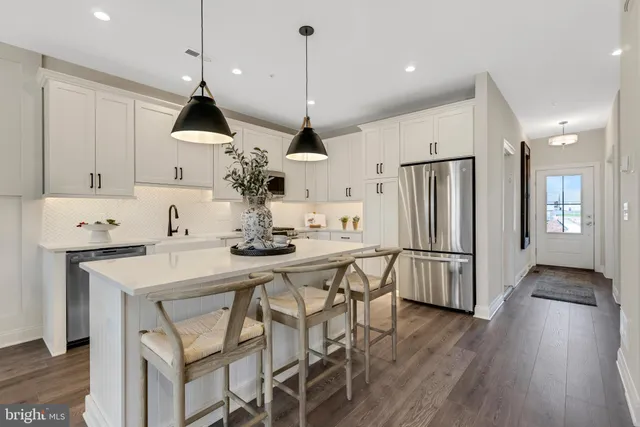 a kitchen with stainless steel appliances a dining table chairs stove and white cabinets