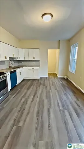 a view of a kitchen with wooden floor and electronic appliances