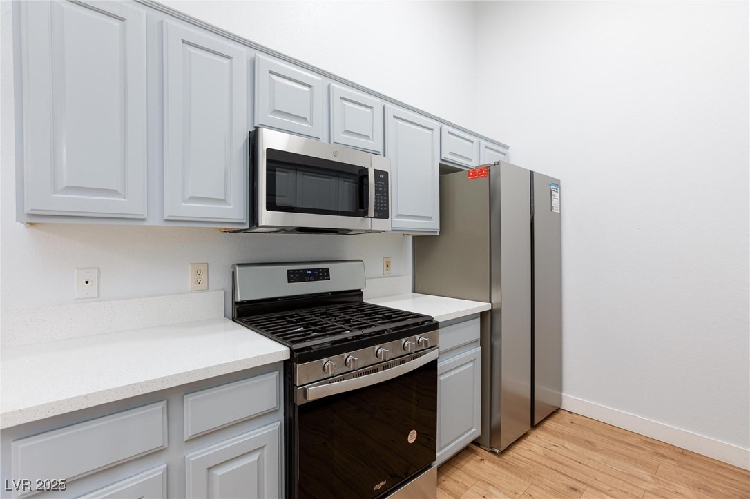 2305 West Horizon Ridge Parkway, Unit 1822 Henderson, NV 89052 - Photo 13 of 34 Kitchen with appliances with stainless steel finishes, light wood-type flooring, light stone countertops, and gray cabinets