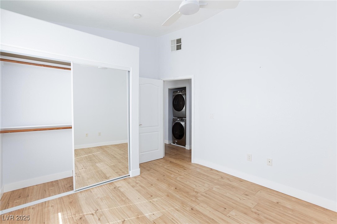 2305 West Horizon Ridge Parkway, Unit 1822 Henderson, NV 89052 - Photo 25 of 34 Unfurnished bedroom with a closet, light wood finished floors, stacked washer / drying machine, and ceiling fan