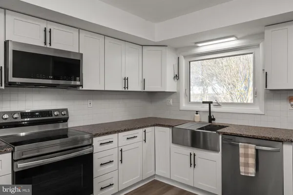 a kitchen with white cabinets stainless steel appliances and a window