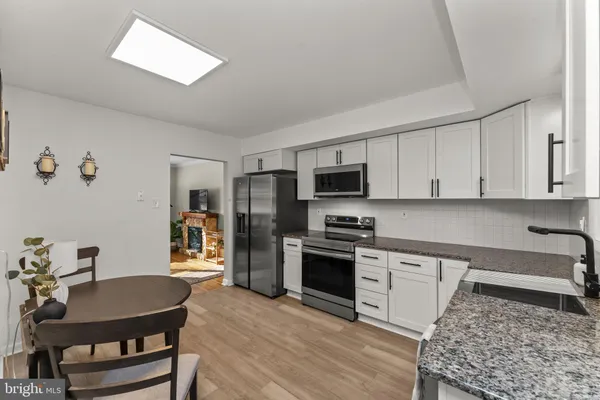 a kitchen with stainless steel appliances granite countertop a stove a sink dishwasher a stove a refrigerator with a dining table and chairs