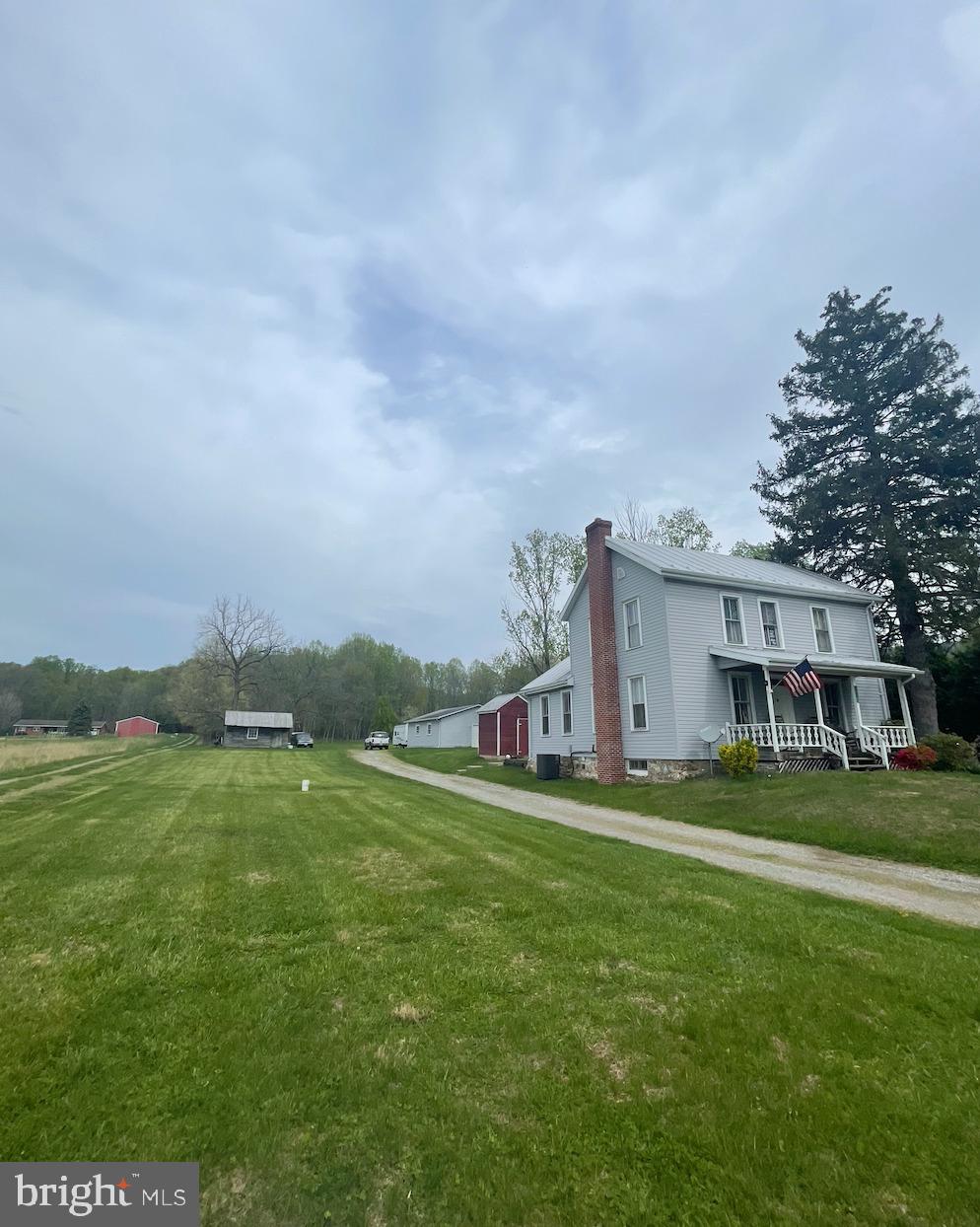 a view of a house with a big yard and large trees