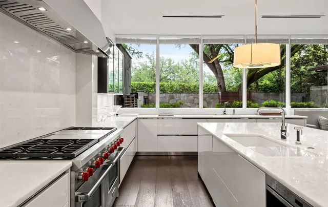 a kitchen with kitchen island a sink appliances cabinets and a large window