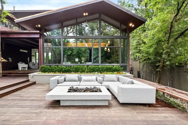 a view of a patio with couches table and chairs under an umbrella