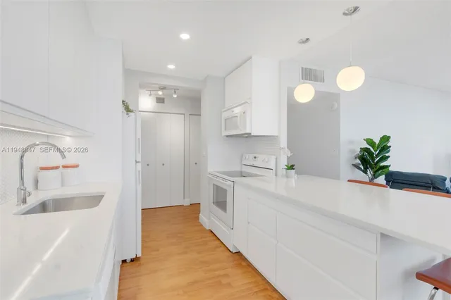 a large white kitchen with a sink and a large mirror