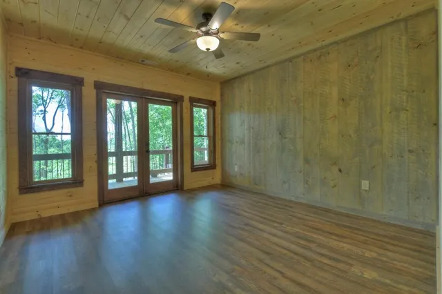 a view of an empty room with wooden floor fireplace and a window