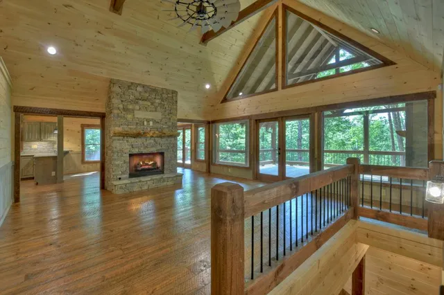 an empty room with wooden floor fireplace cabinet and windows