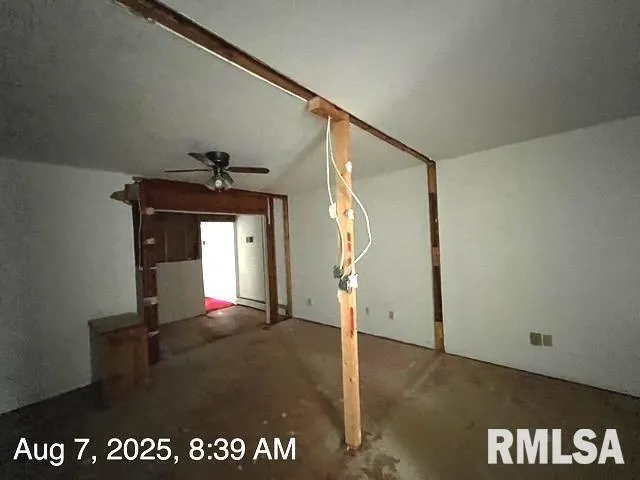 a view of an empty room with wooden floor fridge and a window