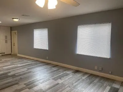 a view of an empty room with wooden floor and a window