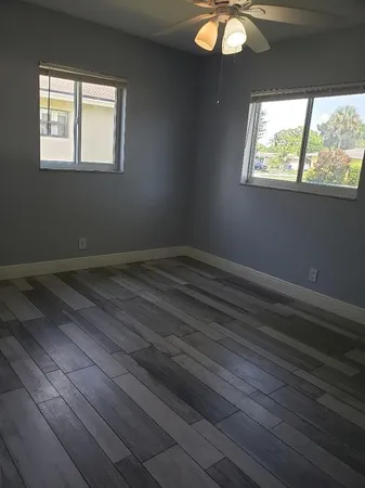 an empty room with wooden floor and windows