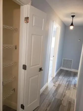 a view of a hallway with wooden floor and a bathroom