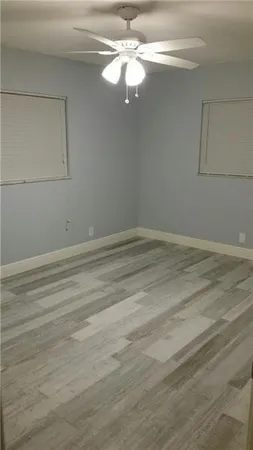 en empty room with wooden floor and fan