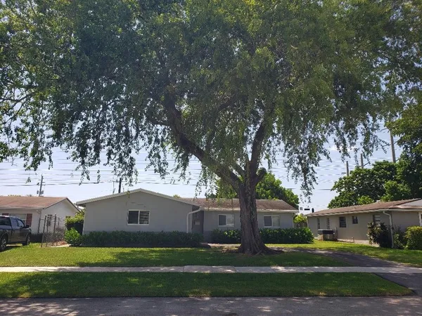 a front view of a house with garden and trees