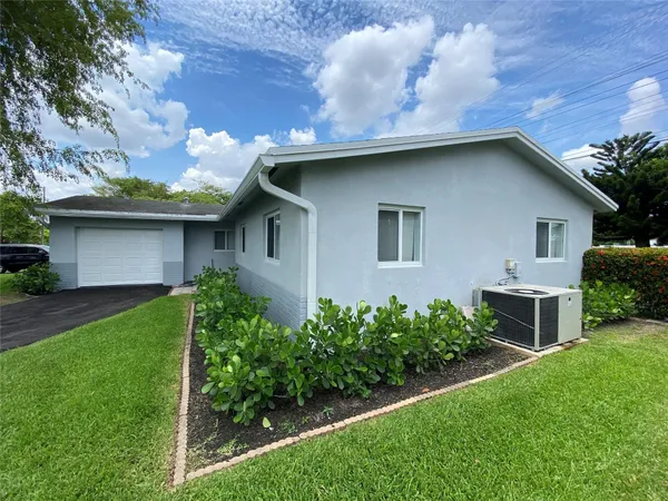 a view of a house with a yard plants and a large tree