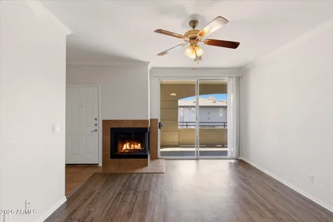 an empty room with wooden floor a ceiling fan and a fireplace