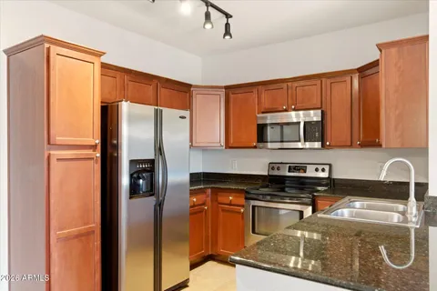 a kitchen with stainless steel appliances granite countertop a refrigerator a stove and a sink with wooden floor