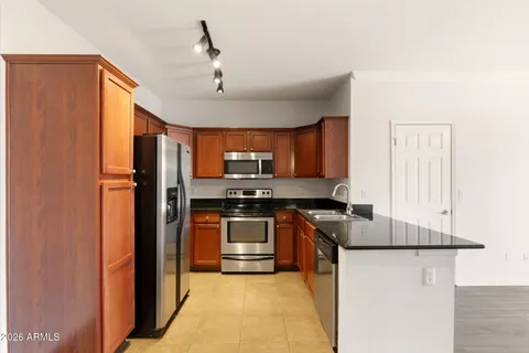 a kitchen with stainless steel appliances granite countertop a refrigerator a stove and a sink